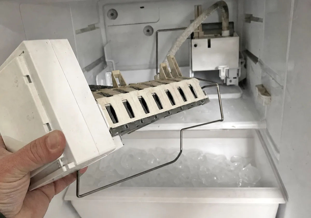 Centre crop of the ice maker module, its white plastic housing and harvest arm filling the frame.
