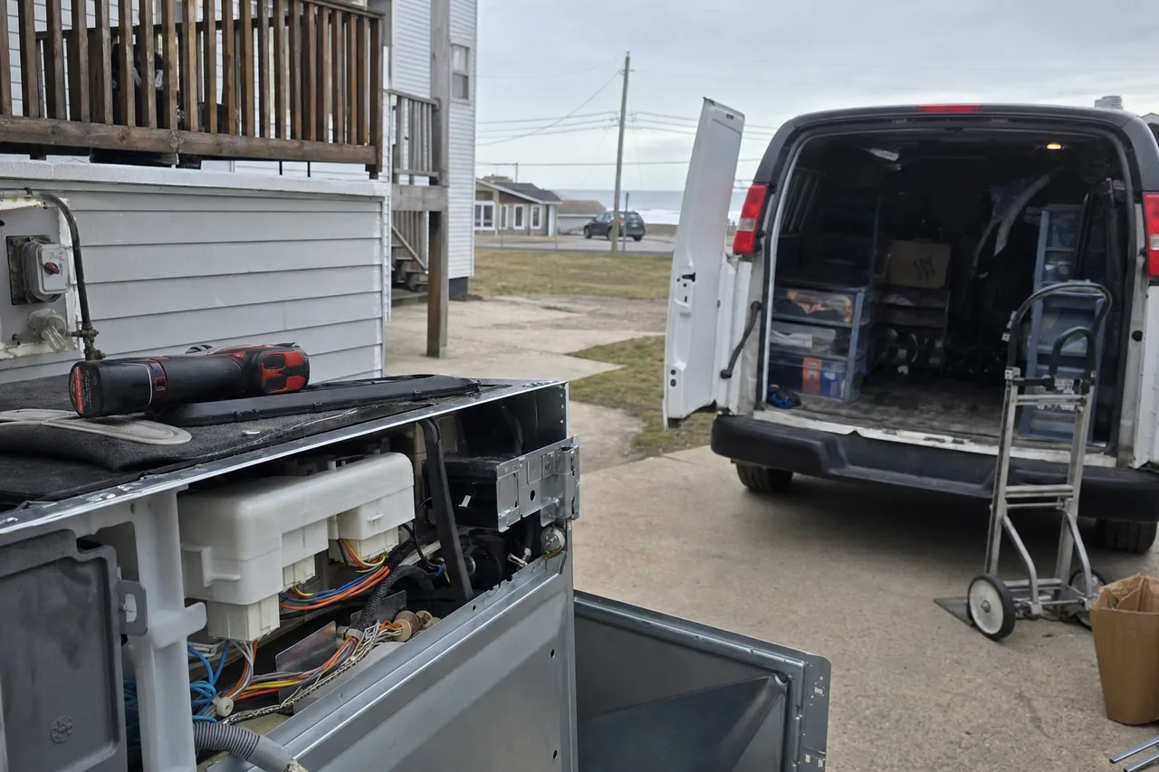 Mirrored view of the open van, the bins stacked to one side and the driveway running back toward the street.